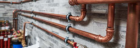 copper gas pipes affixed against a brick wall in a house's basement