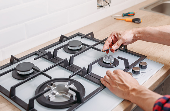 a person installing gas hobs into a kitchen countertop